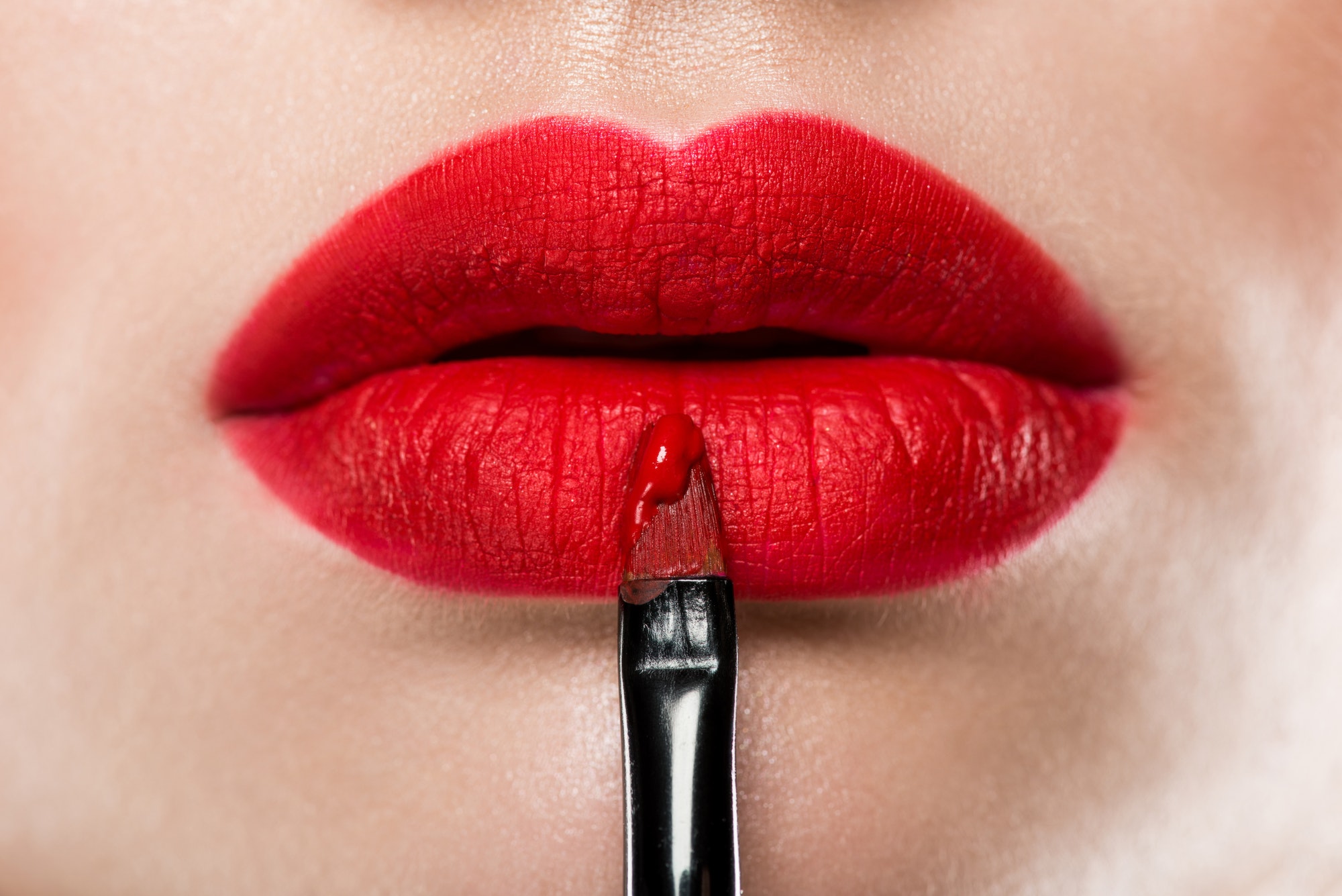 close-up-view-of-elegant-woman-applying-red-lipstick-with-cosmetic-brush.jpg
